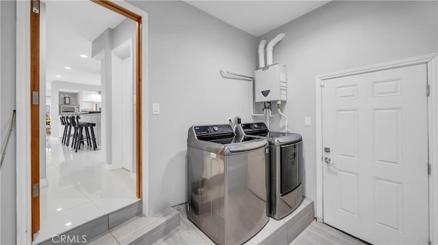 clothes washing area featuring laundry area, water heater, and separate washer and dryer