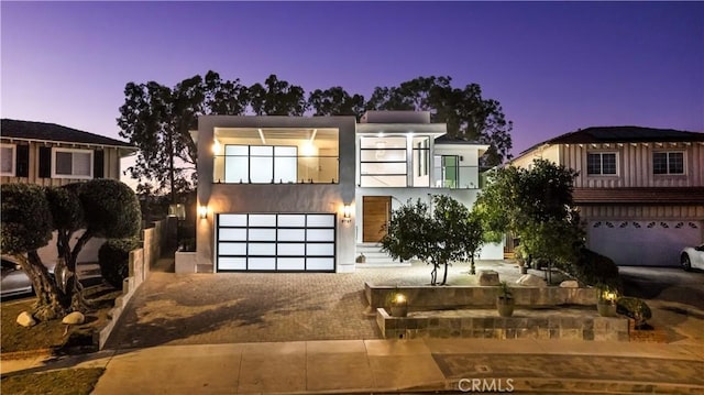 view of front of house featuring a balcony, stucco siding, driveway, and a garage