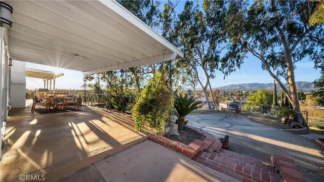 view of patio / terrace featuring outdoor dining area, fence, and a mountain view