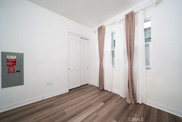 interior space with electric panel, baseboards, and wood finished floors