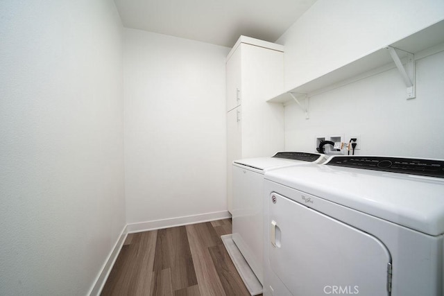 laundry room with dark wood-style flooring, washing machine and clothes dryer, cabinet space, and baseboards