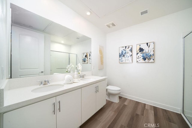 bathroom featuring visible vents, toilet, wood finished floors, a shower stall, and a sink