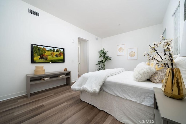 bedroom with baseboards, visible vents, and wood finished floors