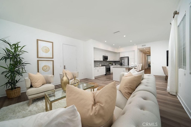 living area featuring recessed lighting, wood finished floors, visible vents, and baseboards