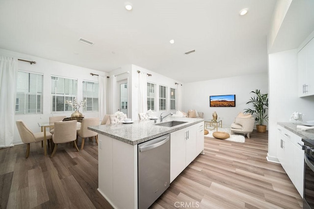 kitchen featuring visible vents, stainless steel dishwasher, light wood-style floors, open floor plan, and a sink