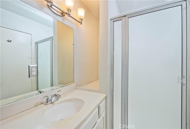 bathroom featuring a shower with door and vanity