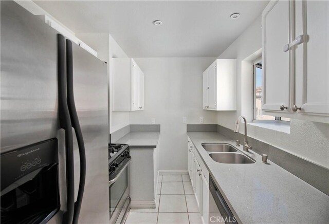 kitchen featuring light tile patterned floors, light countertops, appliances with stainless steel finishes, white cabinets, and a sink