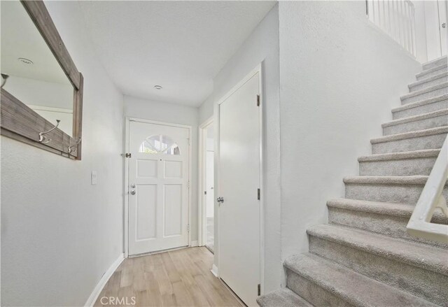 entryway with stairway, baseboards, and wood finished floors