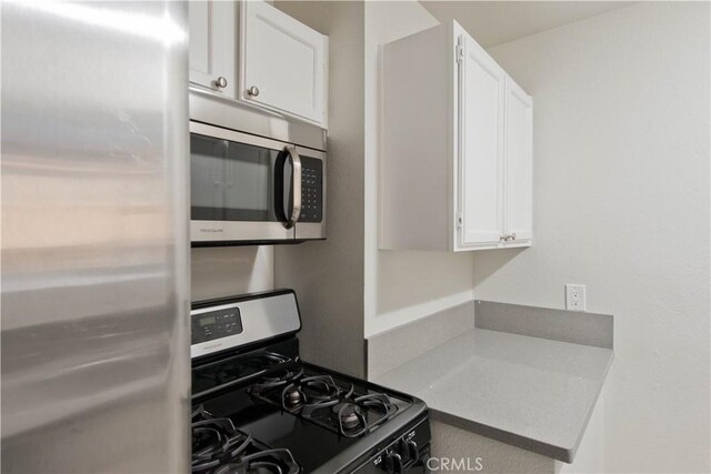 kitchen featuring stainless steel appliances, light countertops, and white cabinets