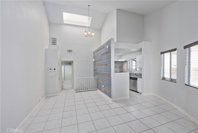 entrance foyer with a skylight, visible vents, a high ceiling, an inviting chandelier, and baseboards