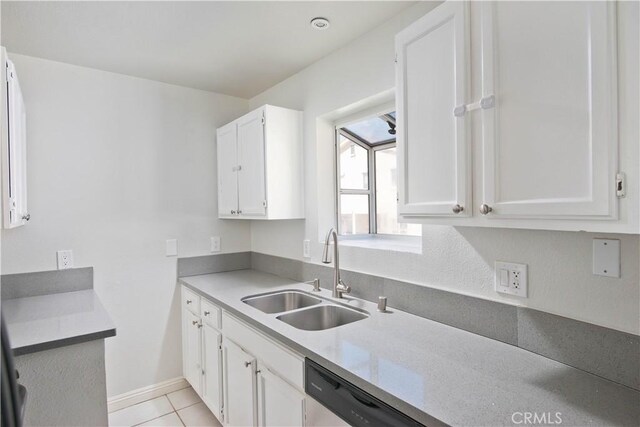 kitchen with light tile patterned floors, a sink, white cabinetry, baseboards, and stainless steel dishwasher