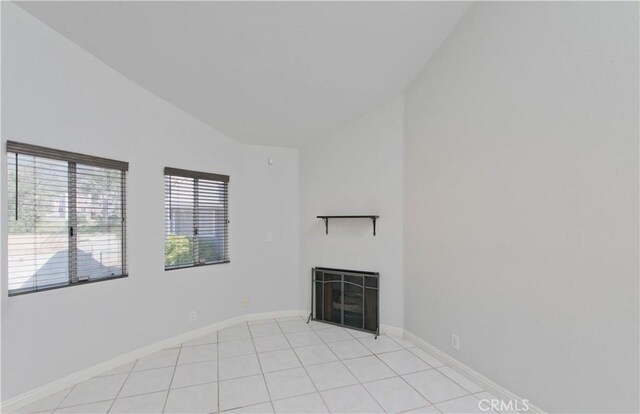 unfurnished living room featuring lofted ceiling, light tile patterned floors, a fireplace, and baseboards