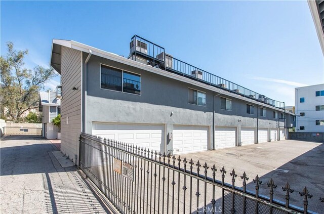 exterior space with stucco siding, fence, and community garages