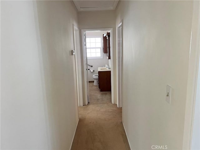 corridor with baseboards and light colored carpet