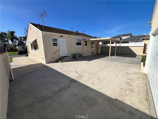 rear view of property with entry steps, a patio, fence, central AC, and stucco siding