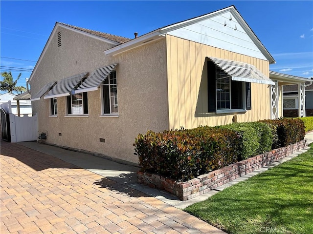 view of side of home featuring fence and stucco siding