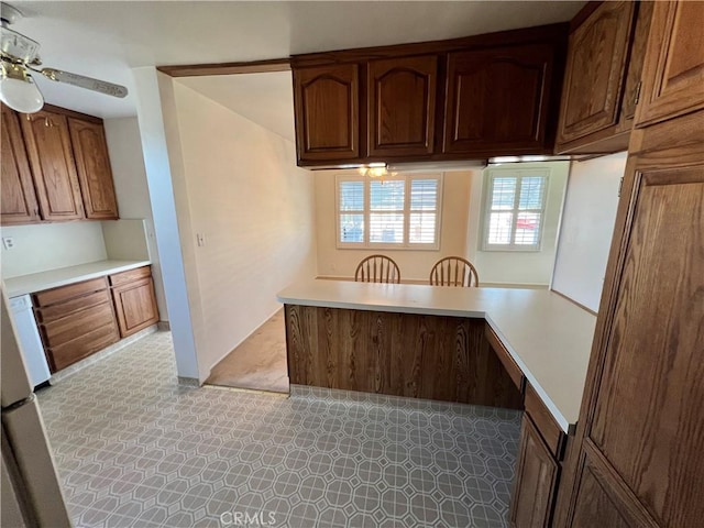 kitchen featuring light countertops, a peninsula, and a ceiling fan