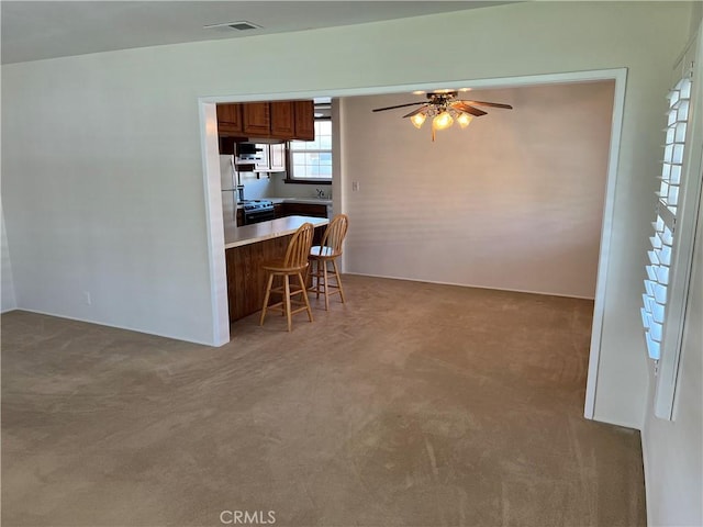 kitchen featuring light countertops, a breakfast bar, carpet flooring, and visible vents