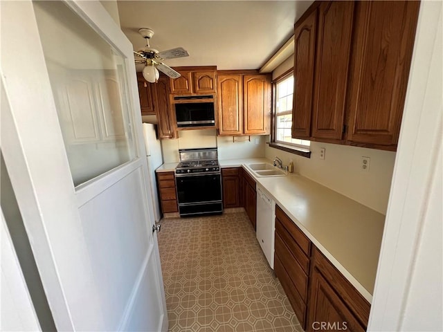 kitchen with light countertops, white dishwasher, a sink, and black gas stove