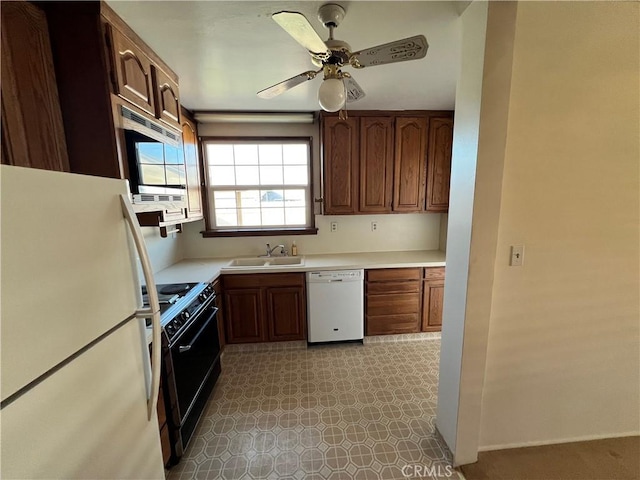 kitchen featuring white appliances, ceiling fan, light countertops, light floors, and a sink