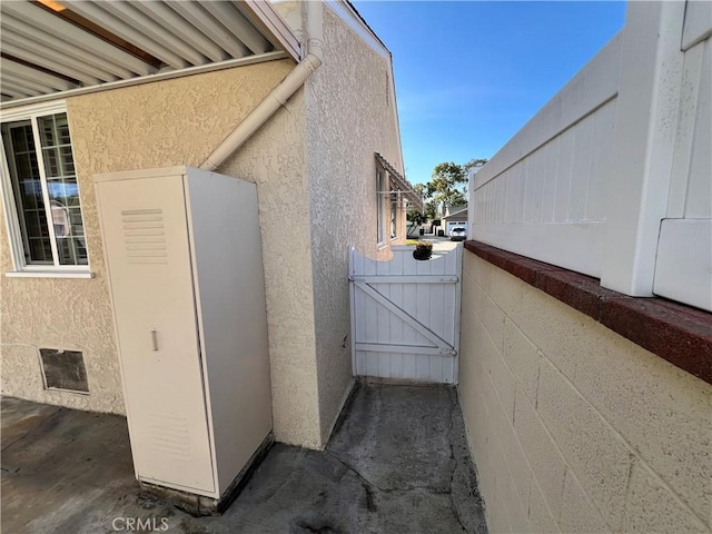 view of side of property with a gate and stucco siding