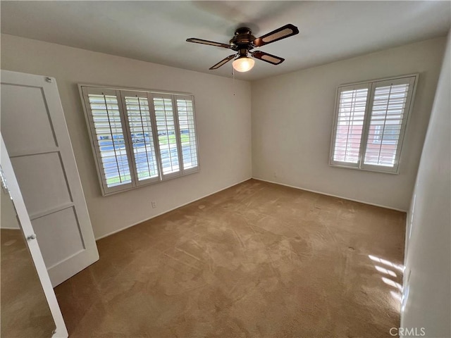 unfurnished bedroom featuring carpet floors, multiple windows, and a ceiling fan