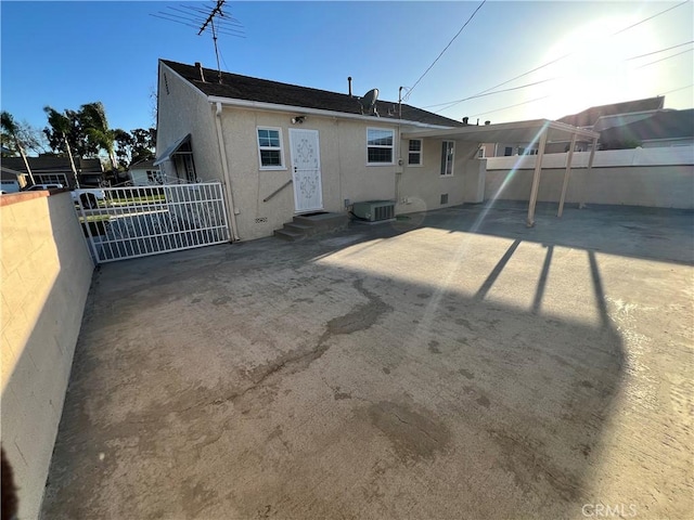 rear view of house with central AC, a patio, fence, and stucco siding