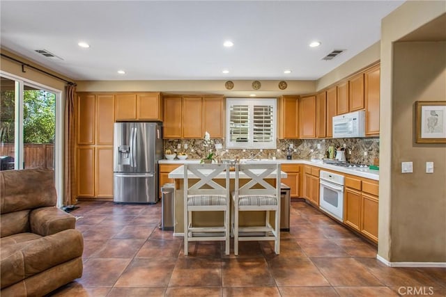 kitchen with light countertops, white appliances, backsplash, and visible vents