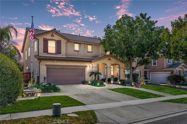 mediterranean / spanish house featuring a garage, a tile roof, concrete driveway, and stucco siding