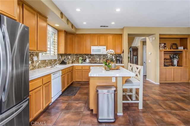 kitchen featuring white appliances, tile counters, a center island, backsplash, and recessed lighting