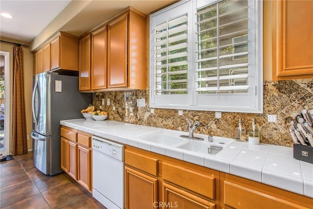 kitchen with decorative backsplash, freestanding refrigerator, dishwasher, and a sink