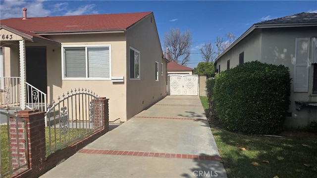 view of property exterior featuring a gate, a detached garage, and stucco siding