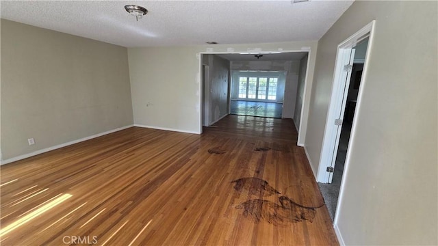 spare room featuring a textured ceiling, wood finished floors, and baseboards