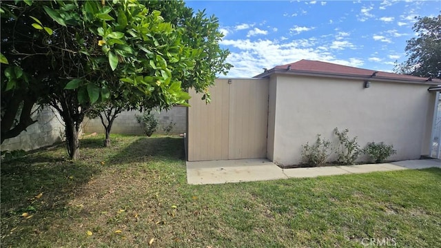 view of property exterior with fence, a lawn, and stucco siding