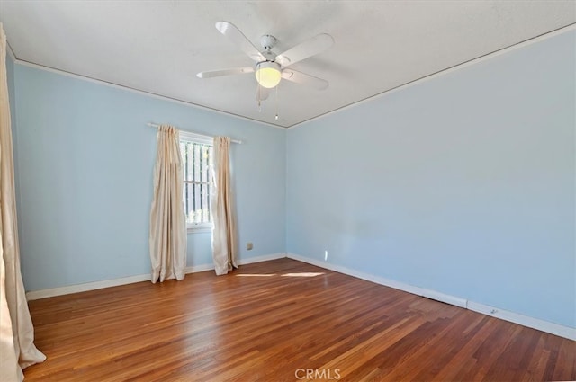 empty room featuring ceiling fan, baseboards, and wood finished floors