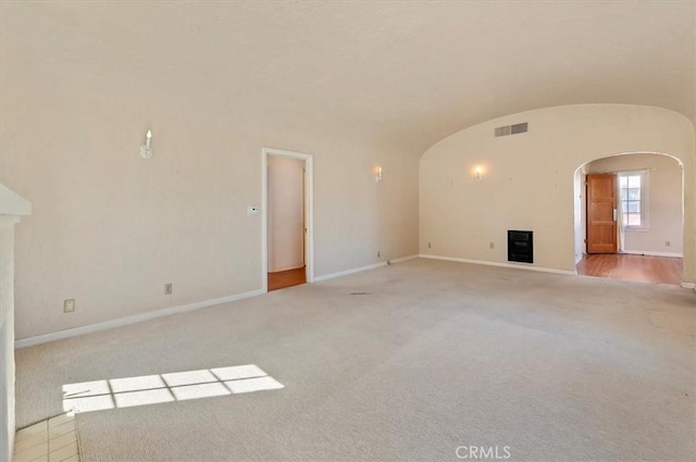 unfurnished living room with baseboards, vaulted ceiling, visible vents, and arched walkways