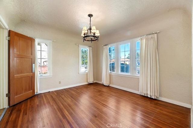 interior space featuring a textured ceiling, baseboards, wood finished floors, and an inviting chandelier