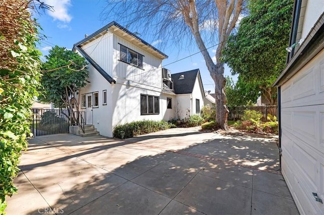 back of property with stucco siding, fence, driveway, and a patio