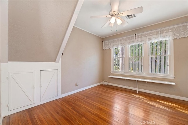 unfurnished room with ceiling fan, wood finished floors, visible vents, baseboards, and ornamental molding