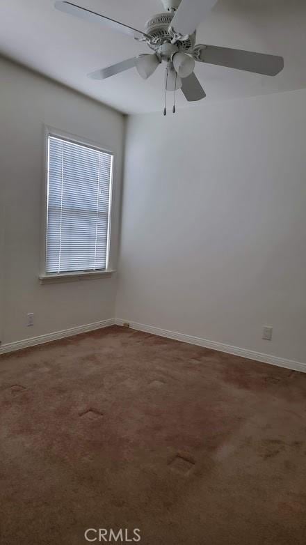 empty room featuring ceiling fan, baseboards, and carpet flooring