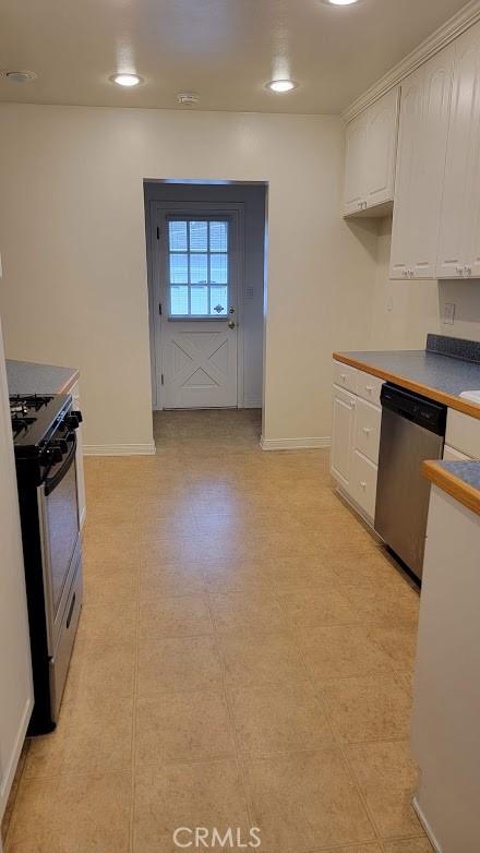 kitchen with appliances with stainless steel finishes, white cabinetry, and baseboards