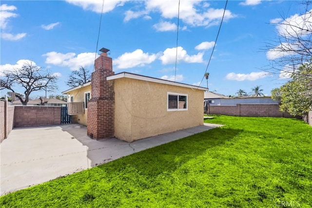 view of side of property with a fenced backyard, a yard, a chimney, and stucco siding