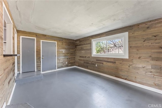 unfurnished room with finished concrete flooring and wooden walls