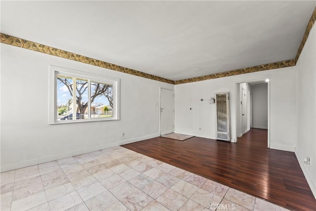 spare room with baseboards and wood finished floors