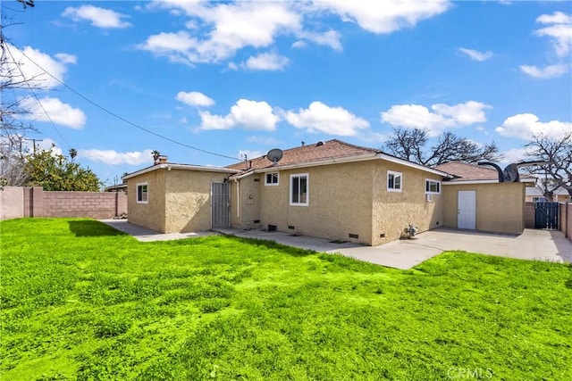 rear view of property featuring a lawn, a fenced backyard, crawl space, a patio area, and stucco siding