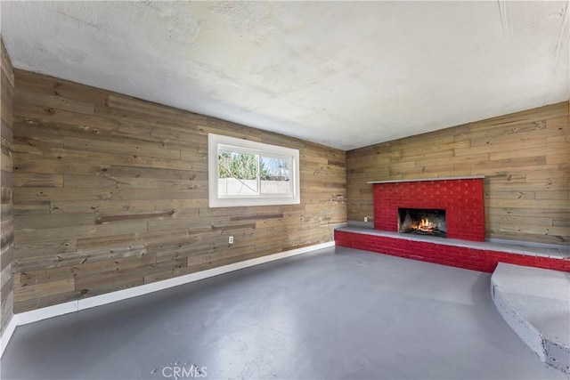 unfurnished living room featuring concrete flooring, a brick fireplace, and wood walls