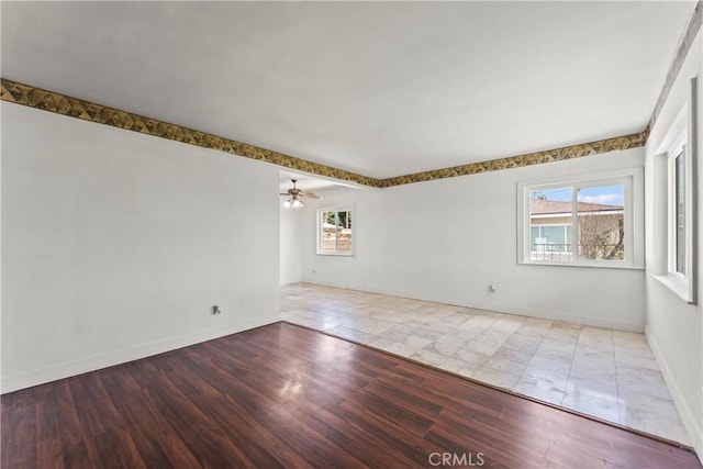 unfurnished room featuring a ceiling fan, baseboards, and wood finished floors