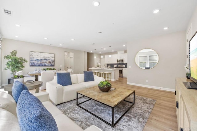 living area with visible vents, recessed lighting, light wood-type flooring, and baseboards