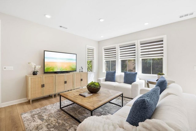 living room featuring light wood finished floors, visible vents, recessed lighting, and baseboards