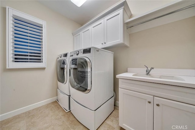 washroom with light tile patterned floors, cabinet space, a sink, washer and dryer, and baseboards